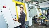 man operating cnc edm machine on factory floor