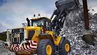 A JCB wheel loader with an Ardent tank handling material at a waste and recycling warehouse