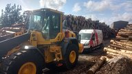 Volvo L70 near wood piles with an ardent van and ardent tank in view